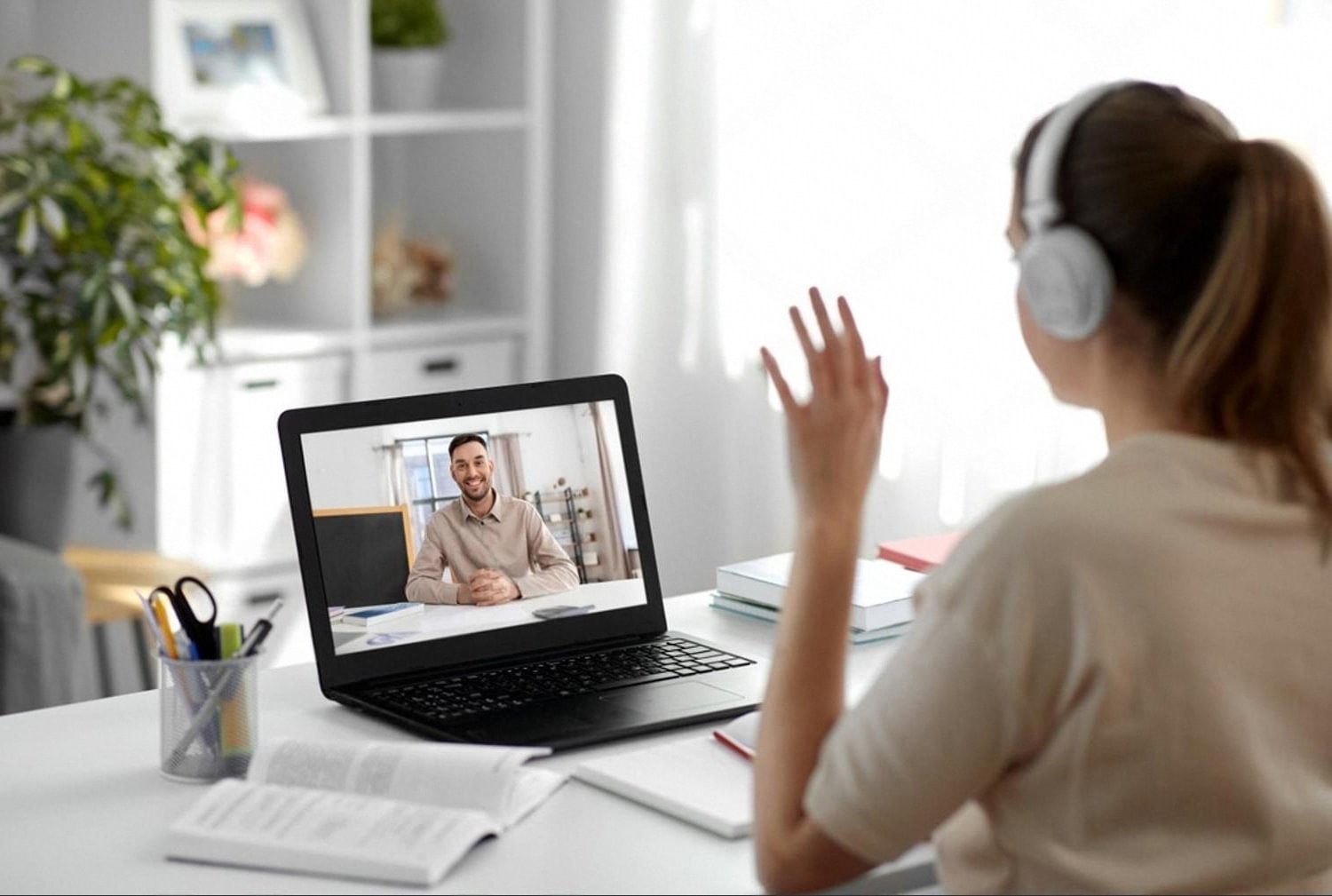 Woman with headphones taking an online class on a laptop at home while balancing full-time work