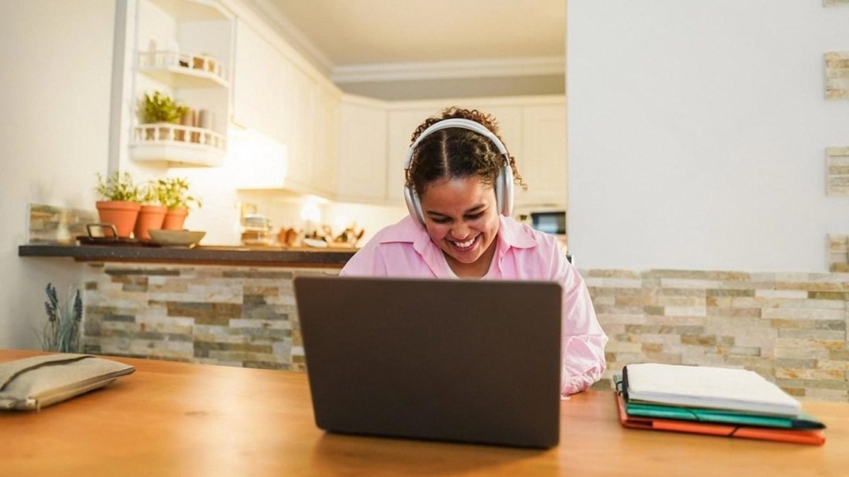 Smiling professional studying on a laptop in a home kitchen after work in the UAE