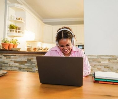 Smiling professional studying on a laptop in a home kitchen after work in the UAE