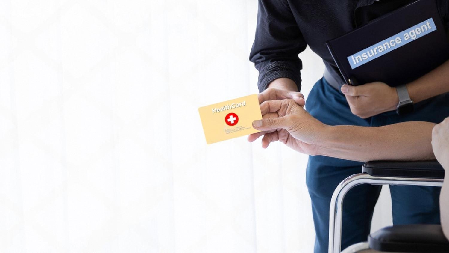 Insurance agent handing a health card to a client in a wheelchair